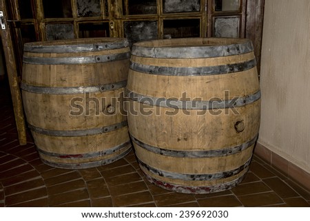 Old oak barrels in the cellar at the entrance to the dark background of the old glass door with broken glass walls in dark colors