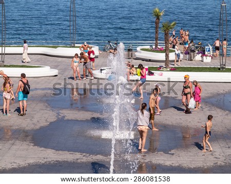 ODESSA, UKRAINE - June 9, 2015: The public beach. Beautiful teen girls in bikinis, women with small children sunbathing on the sand and zhezlongi. Holiday season. Seacoast. Rest area.