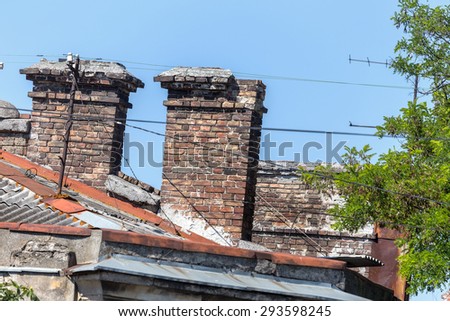 The roof of the old building. Old damaged chimneys of brick and broken television antenna. Creative background for retro design. Background destruction.