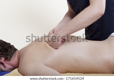 a physiotherapist treats a patient. the back is massaged