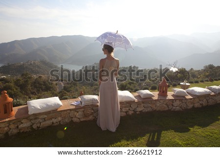 Woman in dress with umbrella on a terrace in the Spanish mountains