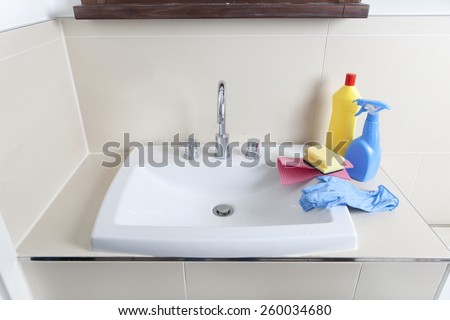 a dirty and calcified sink with cleaning gloves and cleaning products