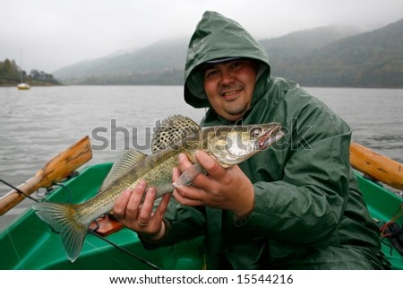 Happy fisherman presents zander, caught big fish