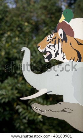 An animal sign at a zoo.   This sign has a duck, a tiger, an elephant and a crocodile on it.