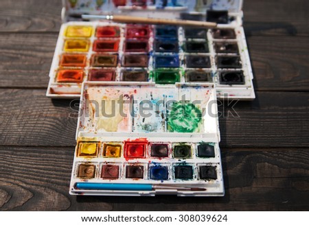 palette of watercolor paints in a dark wood.big and small box of multi-colored paints