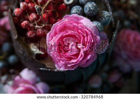 beautiful designer cake decorated chocolate slices, berries and fresh flowers on a brown wooden background