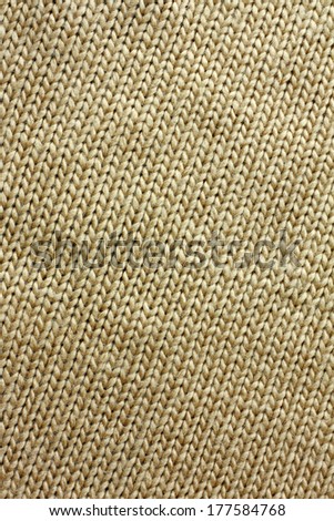 a background of tweed tan or camel colored knit fabric is braided in lines