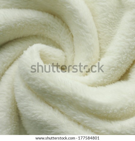 a warm, white, plush micro fleece fabric  blanket is swirled into a circular pattern background