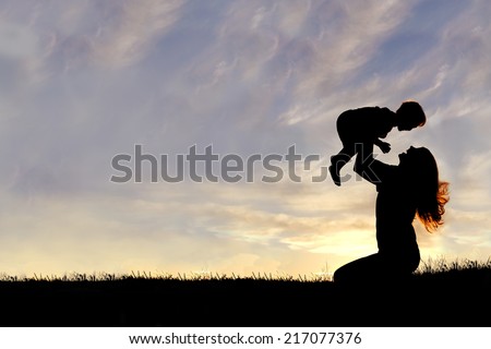 A silhouette of a happy young mother, laughing as she plays with her toddler child and lifts him over her head outside, isolated against the sunset.