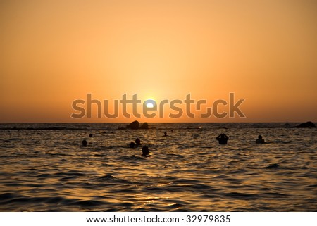 sunset at coast of the sea with people swimming