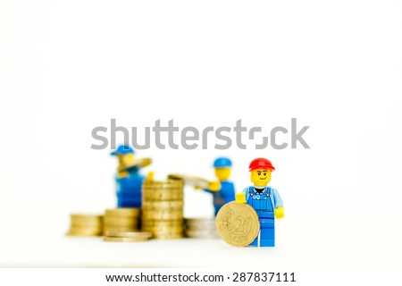 Orvieto, Italy - June 16th 2015: Group of Lego mini figure building a tower of coins. Save a money. Lego is a popular line of construction toys manufactured by the Lego Group
