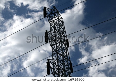 Tall electrical towers with cable wires providing electricity as dark stormy clouds are looming overhead