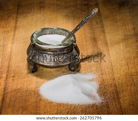 Salt-cellar with spoon on wooden background