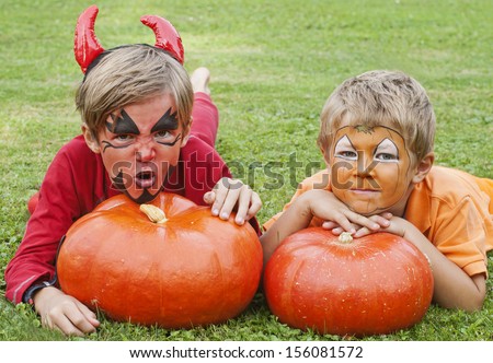 Mischievous, cute boys dressed as a devil and pumpkins for Halloween