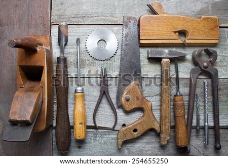 Old hand tools table. Old rusty and dirty carpenter hand tools lying on a wooden table background.