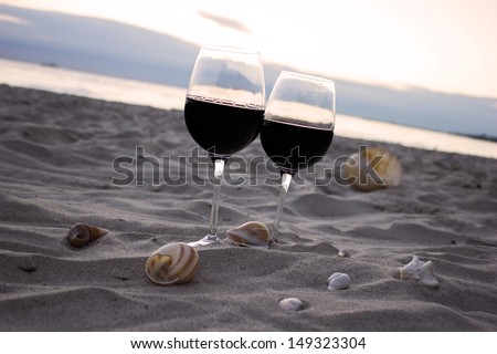 Romantic beach evening: two glasses of wine, candles, shells