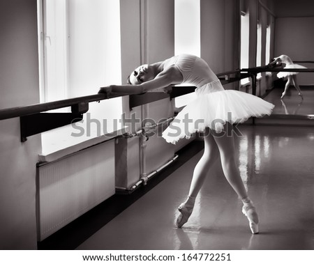 Ballerina posing, reflection in the mirror on the background