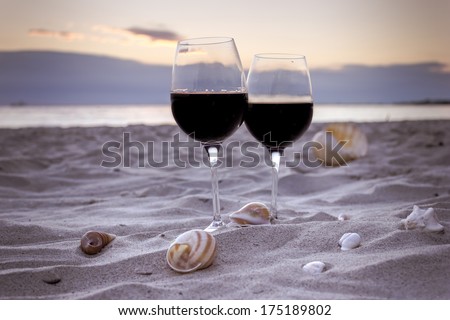 Romantic beach evening on the sunset: two glasses of wine, candles, shells, valentines day