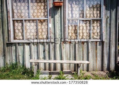 Old wooden house facade with windows and bench