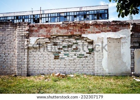 Abandoned factory behind old brick fence on a sunny day