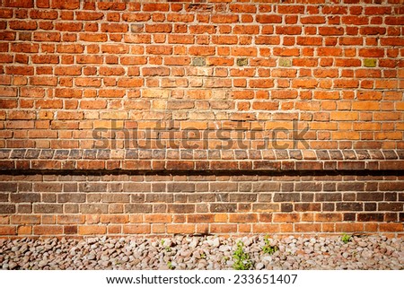 Red brick wall background with some stones on ground