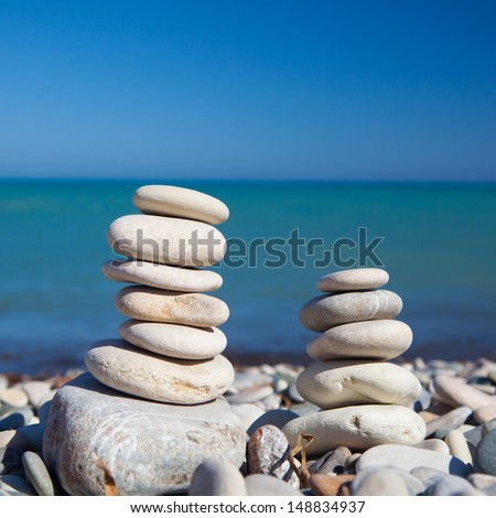 Zen stones on the beach, blue sea background