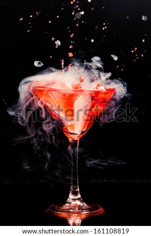 red cocktail with splash and ice vapor