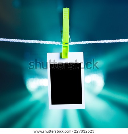 blank photo hanging on rope, blue lights background