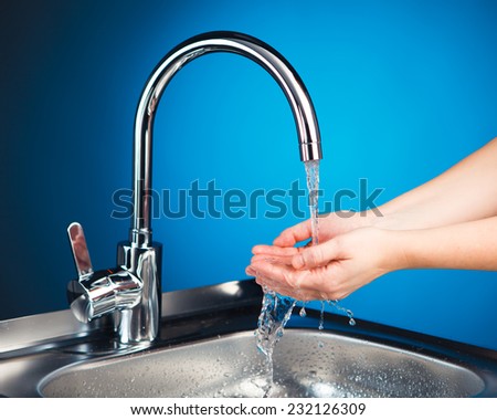 mixer tap with water and washing hands, blue background