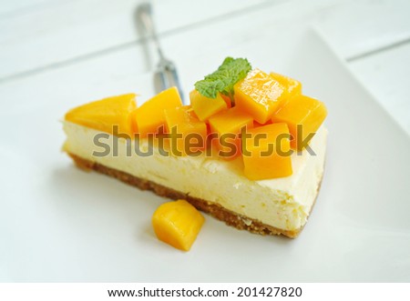 Mango cheesecake on white plate with fork