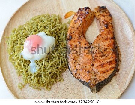 Grilled salmon with green noodle with egg on wooden dish.