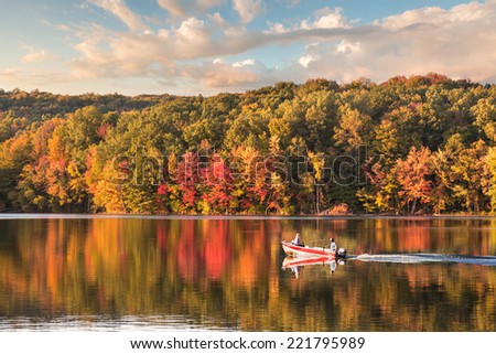 beautiful fall reflections in a lake with a fishing boat during sunset