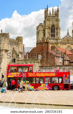 YORK, ENGLAND - MAY 20: A red sightseeing tour bus picking up customers - with York Minster in the background. In York, England, on 20th May 2015.