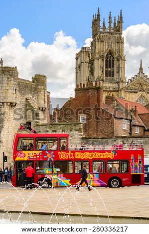 YORK, ENGLAND - MAY 20: A red sightseeing tour bus picking up customers - with York Minster in the background. In York, England, on 20th May 2015.