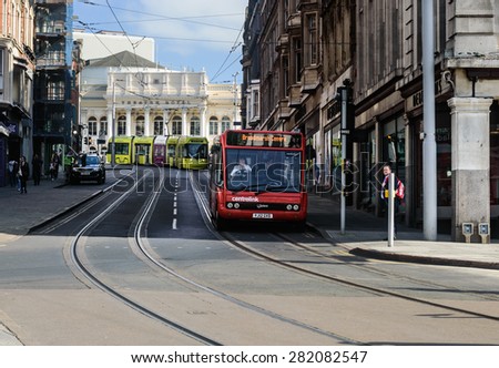 NOTTINGHAM, ENGLAND - MAY 26: A Nottingham NCT tram behind a red \'Trent\' bus, on Market Street, in Nottingham, England. On 26th May 2015.