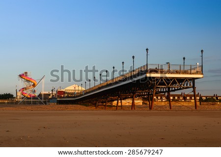 SKEGNESS, ENGLAND - JUNE 8: Skegness pier, the beach, and the fair ground, early morning, in June. In Skegness, Lincolnshire, England on 8th June 2015.