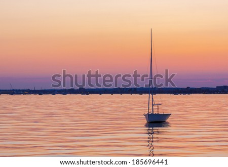 Yacht silhouetted against a pink and purple sky on calm seas inside Poole harbor