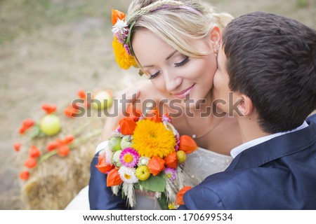 Groom kiss bride\'s neck. Bride holding bouquet of flowers