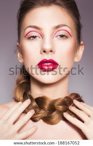 Beautiful brunette woman with red full lips and red lines on her eyelids and braid hairstyle