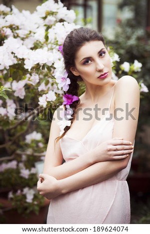 Portrait of a beautiful brunette woman in pink dress and colorful make up outdoors in azalea garden