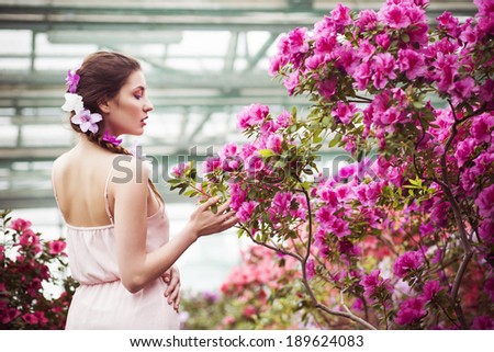 Portrait of a beautiful brunette woman in pink dress and colorful make up outdoors in azalea garden. Copy Space