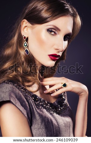 Brunette beautiful luxury woman in dress with clear skin and evening dark make up: green cat eye and brown eyeshadows. Waved hairstyle. Dark background