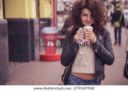 Brunette beautiful stylish caucasian woman in casual outfit on a walk on european city street drinking coffee. copy space
