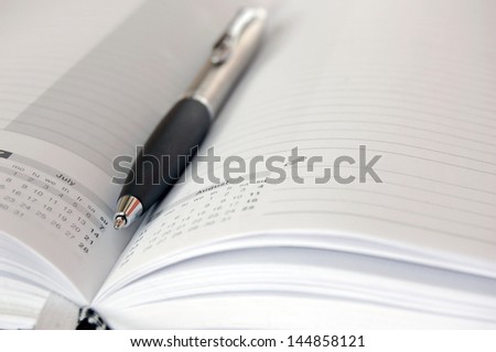 opened business diary with a ball pen