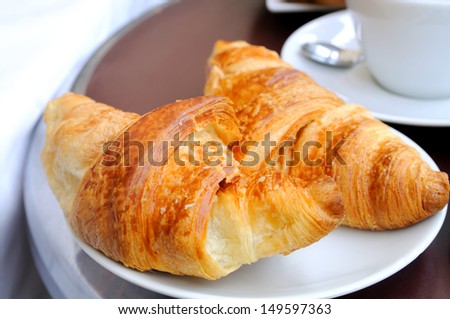 close-up of french breakfast with croissants in white plate and coffee in background