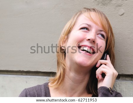 Outdoor portrait of smiling charming young woman on phone