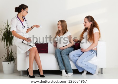 Two pregnant women talk to the doctor in clinic.