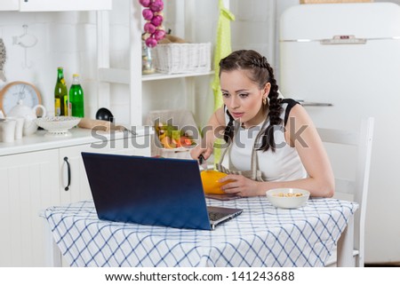 Beautiful woman in an apron with notebook cooks in the kitchen.