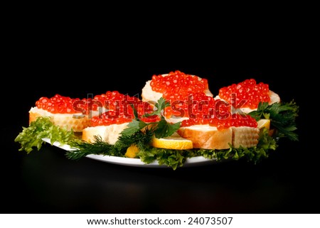 Sandwiches with red caviar and greens on a black background