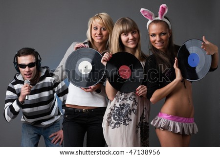 Male DJ and beautiful girls with vinyl disks on a grey background